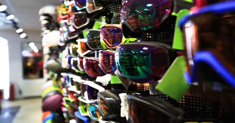 A bunch of goggles on wall while deciding what color goggles for night skiing.