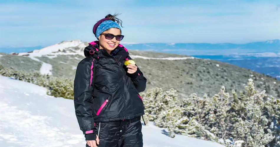 Skier snacking on apple.