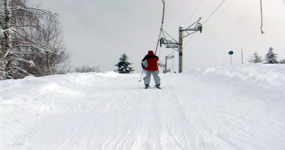 Skier riding Poma lift at ski resort.