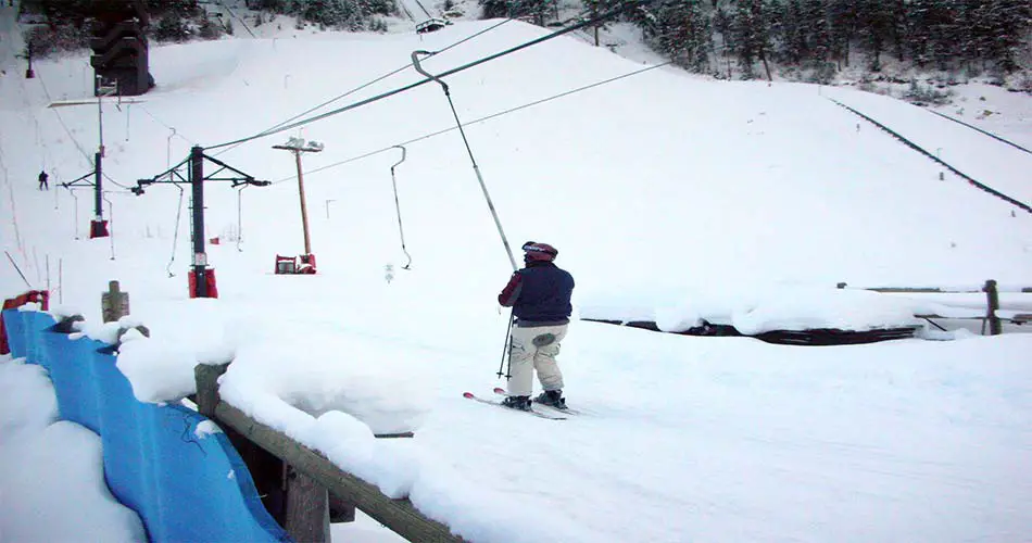 Skier showing how to ride a poma lift correctly.