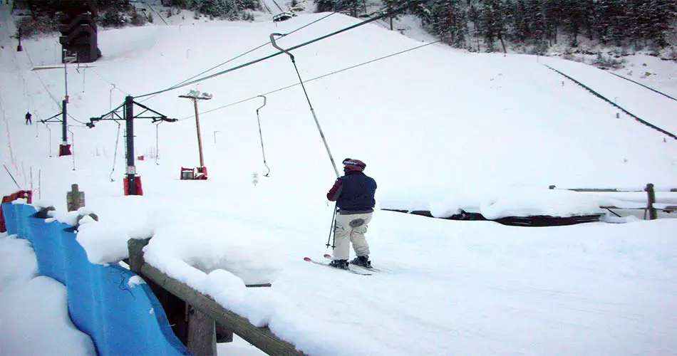 Skier on Poma lift, riding correctly.