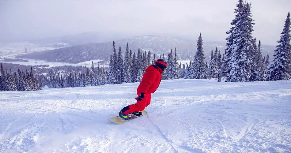 Snowboarder doing riding a toeside turn.