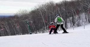 Parent using a child ski harness.