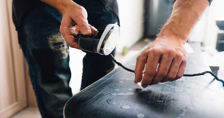 Dripping wax on snowboard with iron.