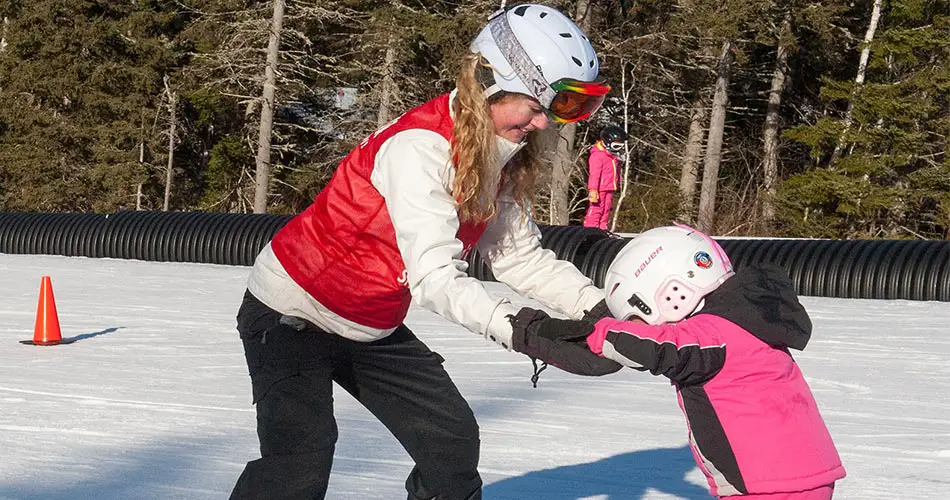 Lady ski instructor teaching child