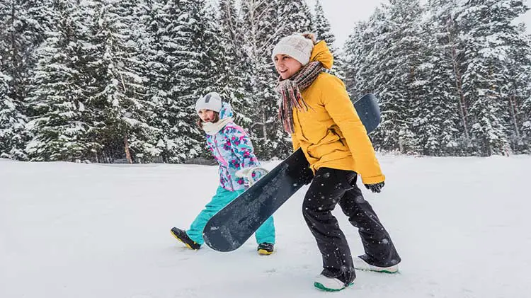 Mom and daughter snowboarders together.