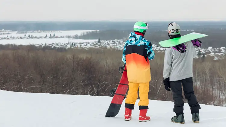 snowboarders looking out over ski slopes