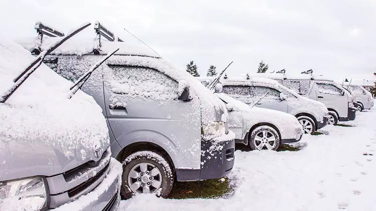 Cars in snow covered parking lot.