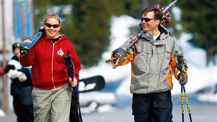 Two people carrying ski equipment