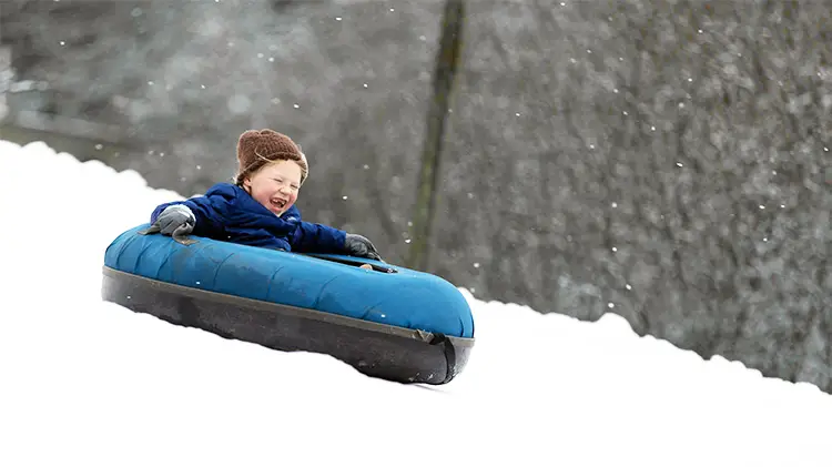 Wolf Ridge boy having fun snow tubing